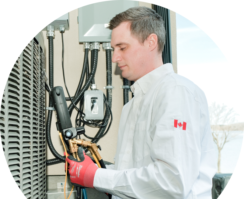 The Comfort Group technician servicing an outdoor air conditioner using a digital refrigerant tool, wearing red gloves and a white uniform. The Comfort Group technician servicing an outdoor air conditioner using a digital refrigerant tool, wearing red gloves and a white uniform.