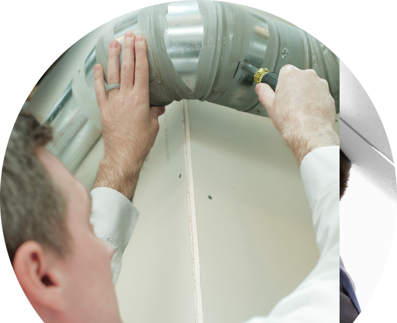 The Comfort Group HVAC technician inspecting and tightening a joint on a sealed metal air duct, performing maintenance work during an air duct cleaning task. The Comfort Group HVAC technician inspecting and tightening a joint on a sealed metal air duct, performing maintenance work during an air duct cleaning task.
