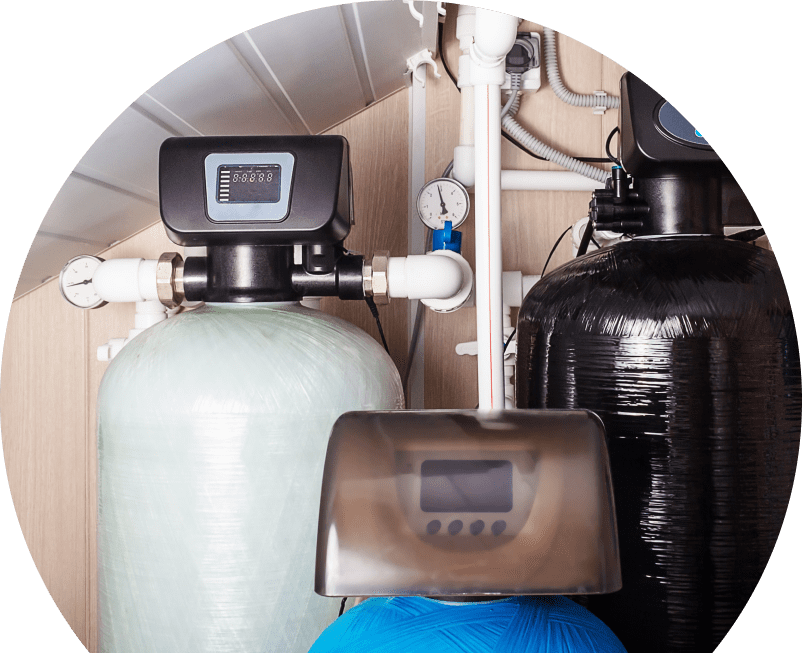 The Comfort Group home water filtration system featuring resin tanks, digital control heads, pressure gauges, and connected piping in a utility room. The Comfort Group home water filtration system featuring resin tanks, digital control heads, pressure gauges, and connected piping in a utility room.