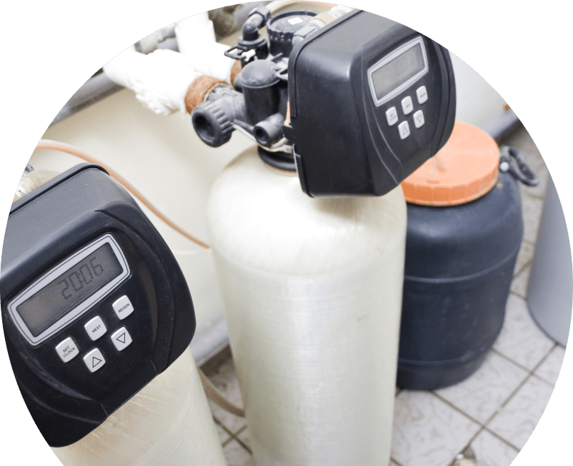 The Comfort Group water softener installation showing dual resin tanks with digital control heads and a brine tank in a tiled utility area. The Comfort Group water softener installation showing dual resin tanks with digital control heads and a brine tank in a tiled utility area.