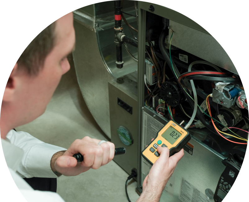 The Comfort Group HVAC specialist performing furnace repair on a heating system, using a digital manometer to check pressure. The Comfort Group HVAC specialist performing furnace repair on a heating sy