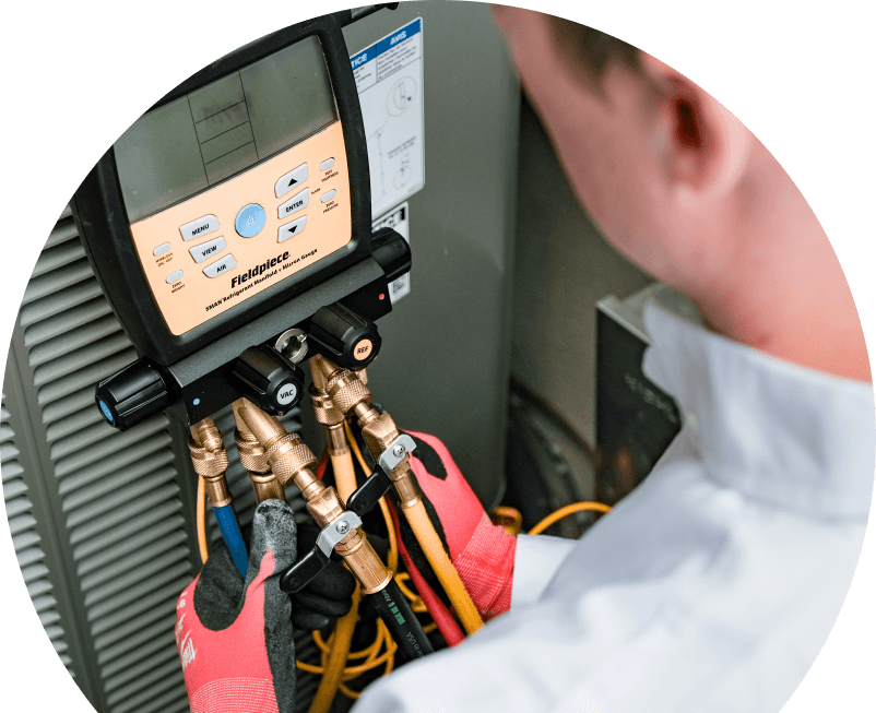 A The Comfort Group home service crew member uses a digital manifold gauge to check refrigerant levels on an HVAC unit for service. A The Comfort Group home service crew member uses a digital manifold gauge to check refrigerant levels on an HVAC unit for service.