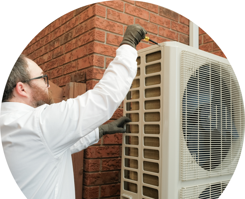 The Comfort Group HVAC specialist using a screwdriver to complete a heat pump installation beside a brick wall. The Comfort Group HVAC specialist using a screwdriver to complete a heat pump installation beside a brick wall.