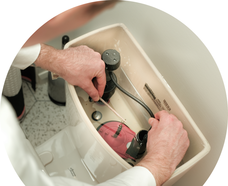The Comfort Group plumbing specialist adjusts internal components of a toilet tank, with tile flooring visible in the background.