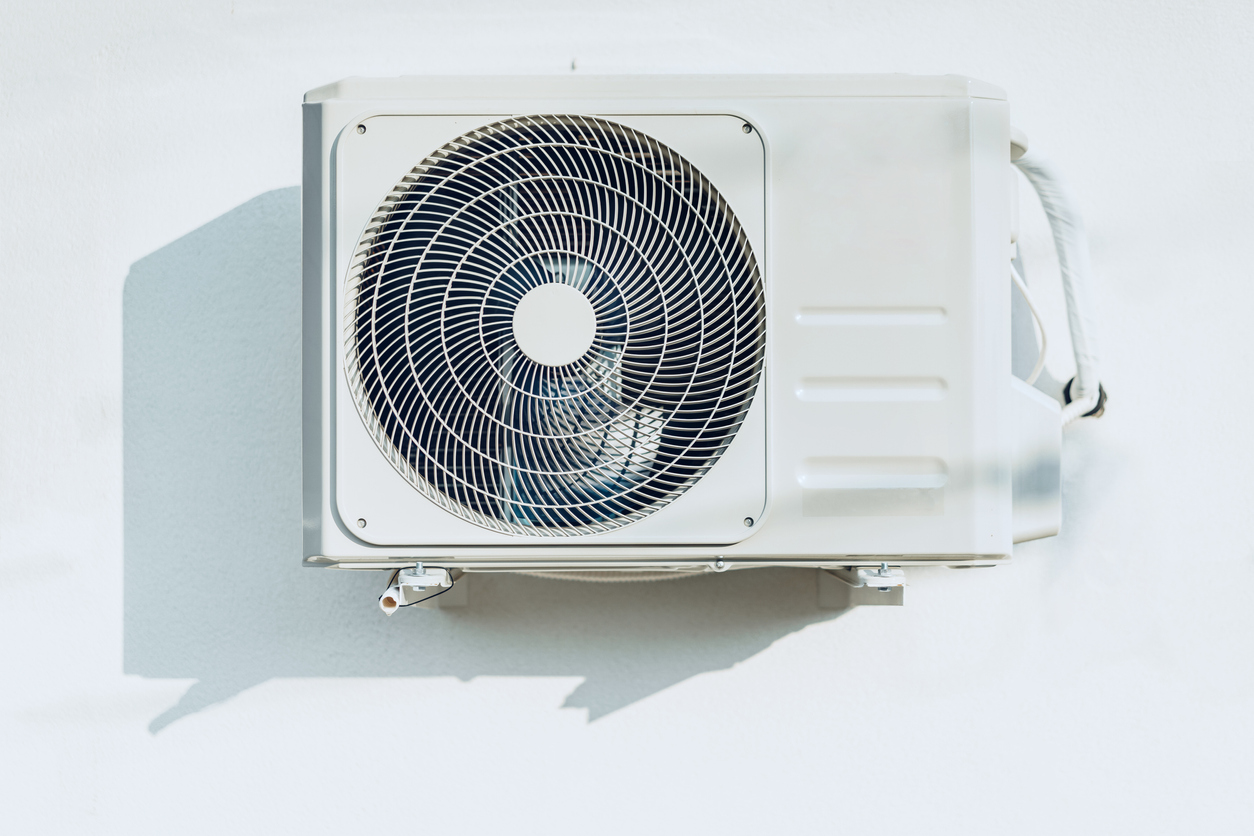 New outside air conditioner unit hanging on white wall New outside air conditioner unit hanging on white wall