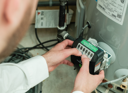 A The Comfort Group technician adjusts the control module on a residential water heater, verifying proper operating settings. A The Comfort Group technician adjusts the control module on a residential water heater, verifying proper operating settings.